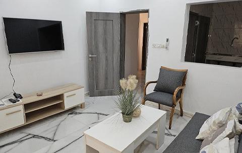 Salon au sol de marbre blanc, télévision murale et fauteuil en bois